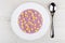Blueberry yogurt with cornflakes in white plate, spoon on table