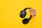 Bluetooth headphones stick out from a yellow torn background. Copy Space. I love music. Like music.