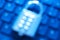 Blur image of metal number combination pad lock on a computer keyboard. Internet and network security theme.Blue tone background