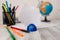 Blur image of stationery plus artificial globe on the wooden table. Lumber desk full with writing equipments and paper
