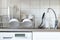 Blur kitchen background with dishwashing machine, water tap, sink, dish rack and plates cups on it, horizontal