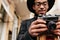 Blur portrait of concentrated african photographer isolated on city background. Outdoor photo of stylish black man with