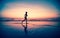 Blured silhouette of a woman jogger on the beach at sunset