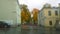 Blurred abstract image of autumn city street, apartment building, orange trees and cars through glass with raindrops. Rainy sad ov