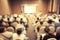 Blurred background of Clouds listening to the Speakers on the stage with Rear view of Audience in the conference hall or seminar