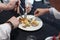 The blurred background of the group of foodies is dividing the food in dish to taste