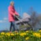 Blurred background of Young women with kids in pram, park, spring season, green grass meadow and bright yellow young