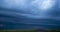 Blurred blue stormy clouds with lightnings float in sky over fields
