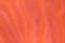 Blurred bright orange and red background with wavy curly pattern. Defocused art abstract ginger gradient backdrop
