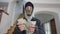 Blurred burglar in mask counting dollars standing in wealthy house indoors. Satisfied Caucasian robber holding cash