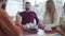 Blurred Caucasian man stretching to phone lying at the foreground and taking his hand back quickly. Group of Caucasian