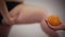 Blurred Caucasian obese woman touching fat legs at the background as female hand holding orange at the foreground