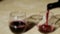 Blurred clip of red wine being poured from the bottle into two glasses.