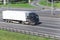 Blurred container driving on the highway with white refrigerator semitrailer