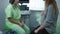 Blurred doctor talking with unrecognizable pregnant patient sitting in hospital. Caucasian gynecologist consulting