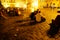 The blurred effect of long exposure movement of people sitting around a cobbled town square under golden glow of night lights