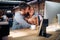 Blurred faces of young man and woman colleagues talking in front of table with desktop computer, in clothing store