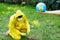 Blurred female hand holding a globe. Behind a man in a yellow suit sets fire to dry leaves. Pollution of the planet