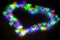 Blurred festive background with defocused colourful glitter formed a heart, bokeh in a shape of a heart. Original photographic