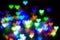 Blurred festive background with defocused colourful glitter formed a heart, bokeh in a shape of a heart. Original photographic