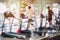 Blurred fitness center with cardio machines and weight, strength training equipment. Figures of humans running on treadmills in