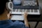 Blurred focus close-up. Male music arranger hands composing song on midi piano and audio equipment in digital recording
