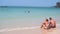 Blurred footage of sea wave hit sand beach, adult tourist couple wearing swimming suit sit on a beach