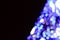 Blurred fragment of the New Year tree. Lots of round lights in blue