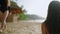 Blurred girl giving coconut cocktail to happy lady at sandy beach with bungalow. Young pretty women rest at the tropical