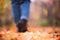 Blurred girl in jeans and boots walks in the autumn forest. Unfocused women`s legs in the Indian summer season