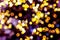 Blurred golden lights abstract background in the night, defocused dark glowing bokeh backdrop, magical yellow illuminated sparkle