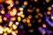 Blurred golden lights abstract background in the night, defocused dark glowing bokeh backdrop, magical yellow illuminated sparkle