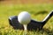 Blurred golf club and golf ball close up in grass field with sunset.