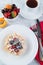 Blurred image of Belgian waffles with powdered sugar and fruit in a plate, cutlery, a cup of coffee and a plate of fruit