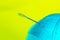 Blurred image of blue thead and needle over yellow background.