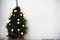 Blurred image of Christmas tree with lights and stylish festive wrapping paper on background of white room. Winter holidays