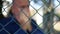 Blurred Image with Disappointed Man Gesticulating in Back of a Metallic Fence