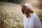 Blurred image of stylish girl in rustic dress smiling and waving hair in sunny meadow in mountains. Portrait of happy boho woman