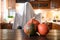 Blurred kitchen with pumpkins on tabletop and child dressing as ghost for Halloween party