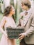 The blurred lovely smiling newlyweds is holding woven box with gray ferrets in the forest.