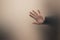 Blurred male hand behind gray matte glass wall