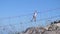 Blurred man walking on the rope on long hanging bridge over the abyss on the grass on foreground in slow motion