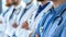 Blurred medical professionals in blue scrubs with focus on foreground.