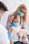 Blurred pediatrician holding syringe near mother