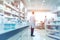 Blurred pharmacy drugstore interior with rows and shelves with medications remedies.Male pharmacist. Medical background