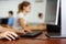 Blurred photo of female teenager in glasses learning computer science while she is using a PC in the computer classroom