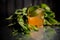 Blurred photo of glass with orange drink among salvia leaves