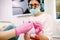 Blurred photo of a stomatology specialist woman doctor in dental loupe binoculars, medical gloves and mask taking some