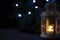 Blurred picture for background. White lantern with a burning candle, pine branch and garland lights on background. Christmas