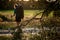 Blurred rear view of woman with backpack through the branches of coniferous tree.